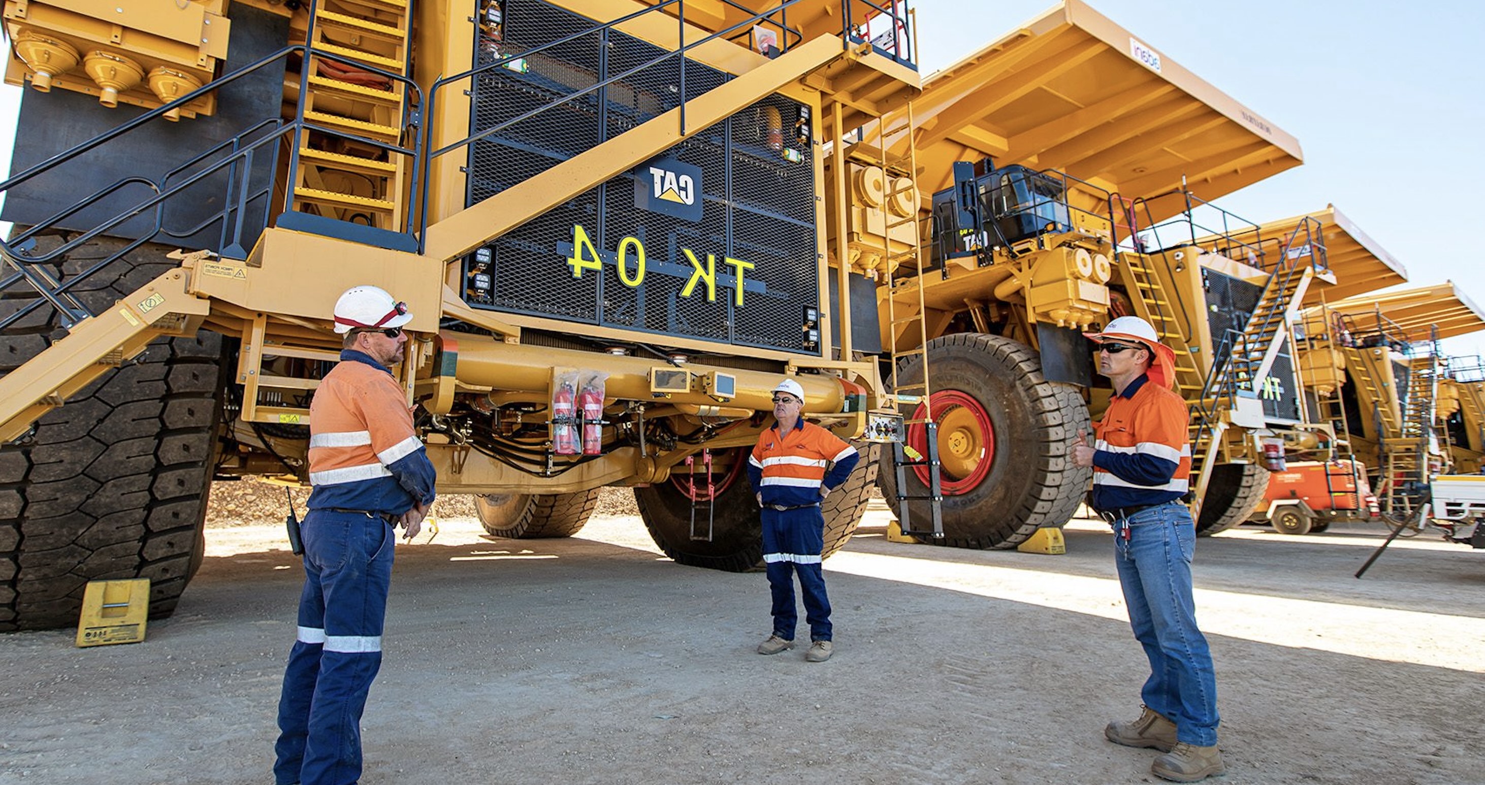 FIFO crew talking in front of haul trucks on an Australian mine site