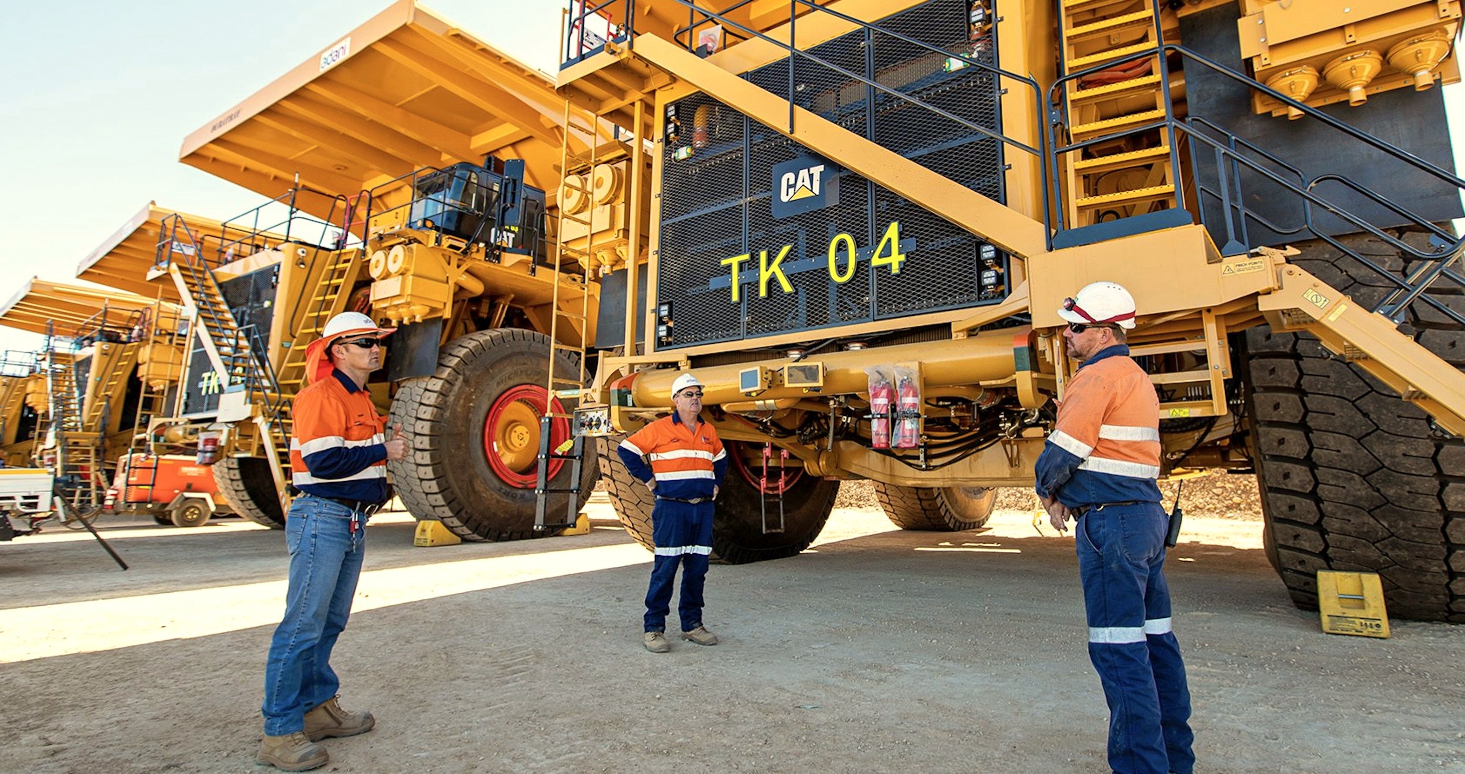 Crew members talking beside the haul trucks ahead of a swing