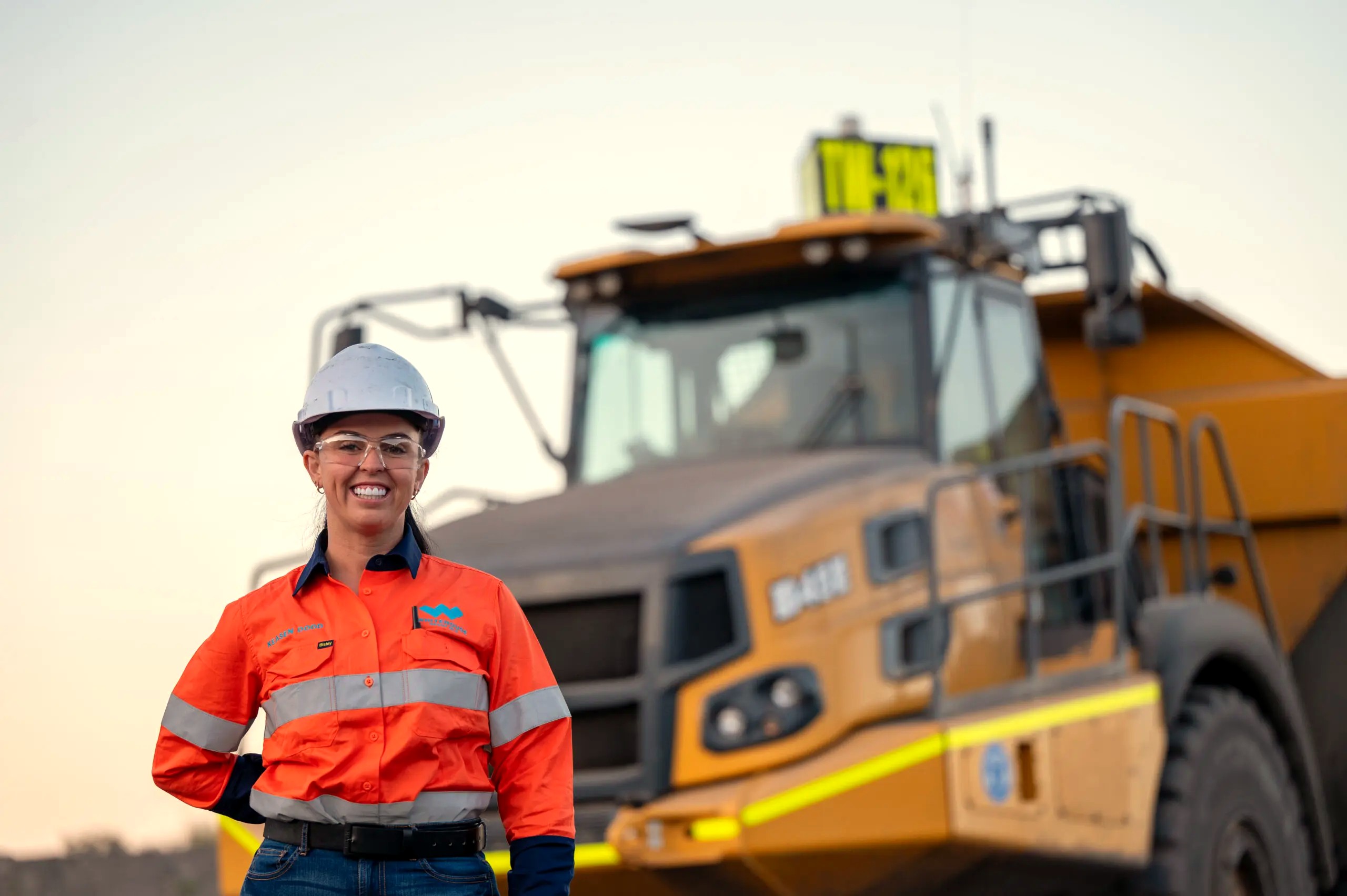 A mining operator standing in front of a haul truck on an Australian site