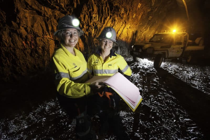 Two mining workers going through the quarterly plan together underground
